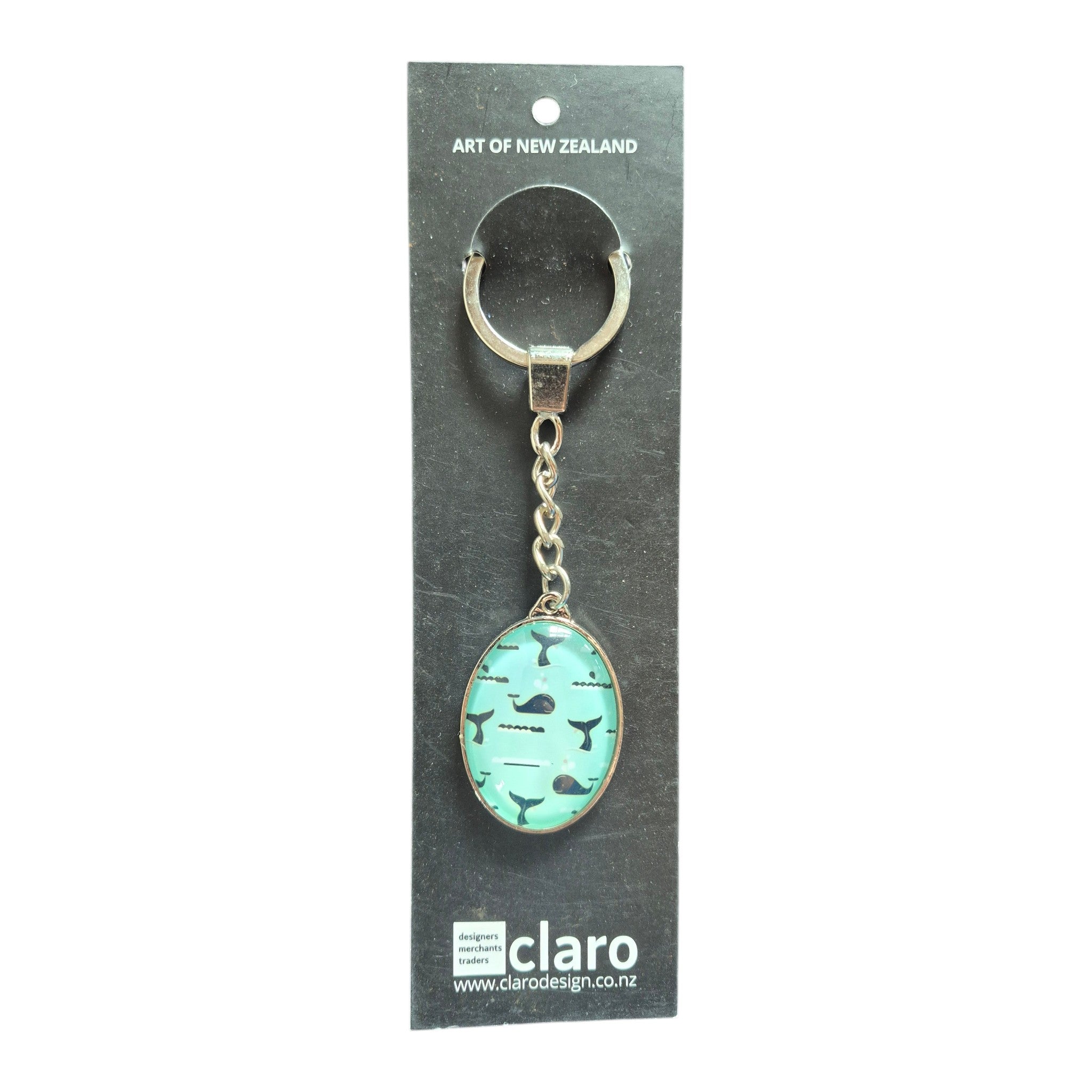 Claro Whale Keychain on display card showing silver oval glass dome with whale and whale tail pattern on aqua background