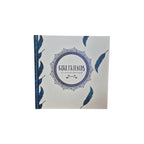 Girlfriends An Unbreakable Bond hardback book — white cover scattered with navy blue feathers and central decorative mandala emblem with teal cloth spine