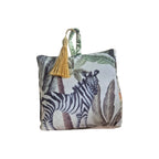 Jungle Velvet Doorstop White by LeForge — front view showing zebra-print side of doorstop with tropical palm and leaf jungle print and gold tassel