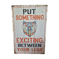 Put Something Exciting Between Your Legs wooden sign — distressed white timber board with bold red and black stencil lettering and vintage winged motorcycle graphic, 60cm x 40cm. NZ