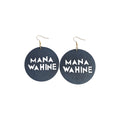 Pair of black round wooden drop earrings with cut-out MANA WAHINE lettering and gold-tone hook ear wires on a white background
