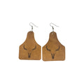 Pair of tan ear-tag-shaped PU leather earrings with dark horned bull skull motifs and silver-tone hook ear wires on a white background