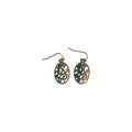 Pair of bronze-tone oval metal drop earrings with openwork scroll swirls, green accents and hook ear wires on a white background